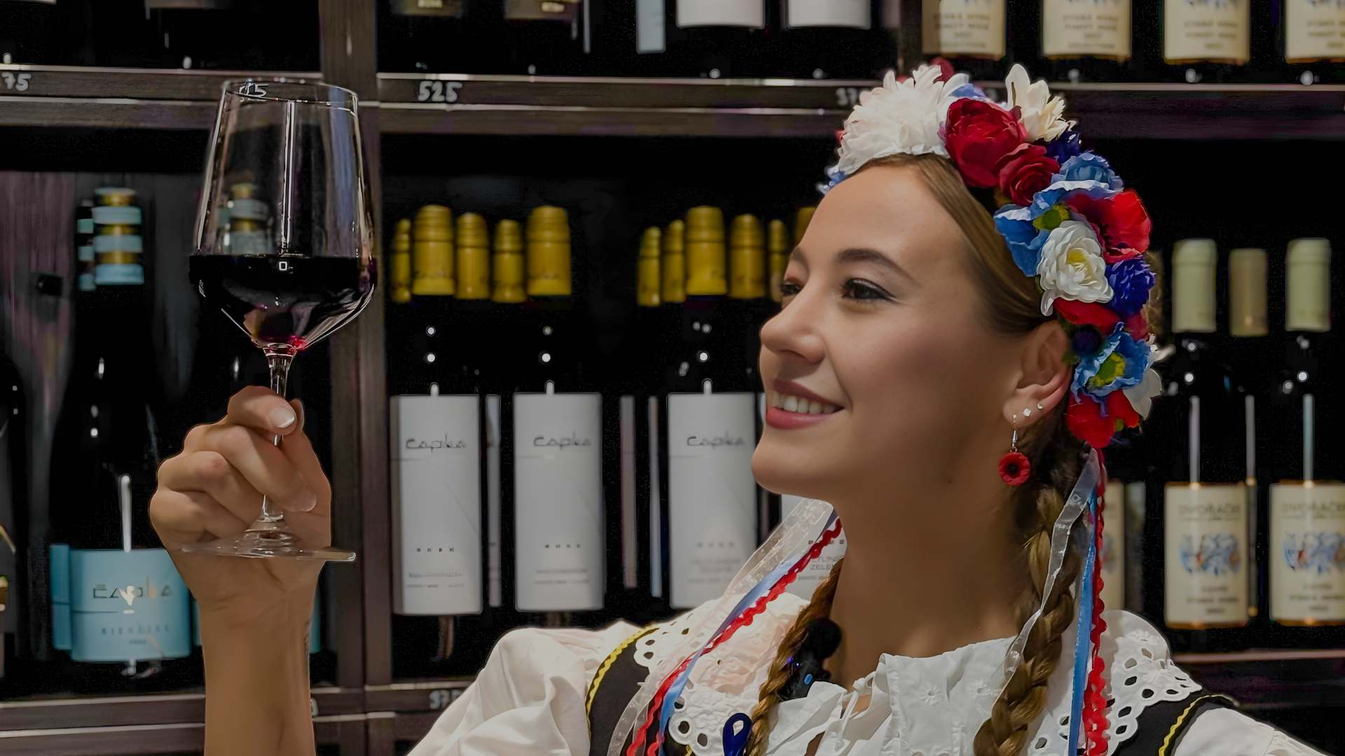 Mladá žena v moravském kroji se sklenkou vína